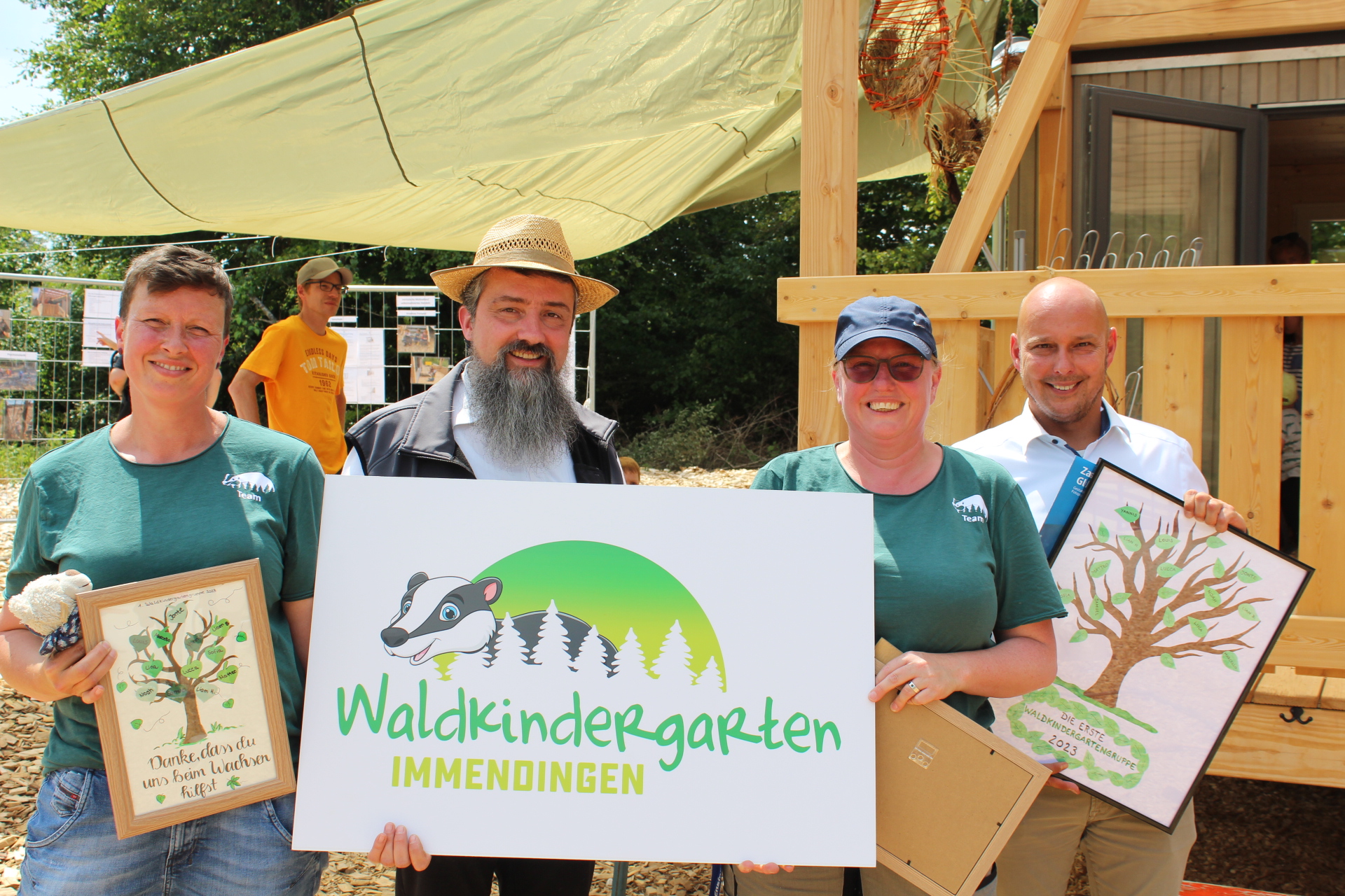 Ein neues Schild gab es zur Einweihung des Waldkindergartenwagens für das Kindergartenteam von Bürgermeister Manuel Stärk (rechts).